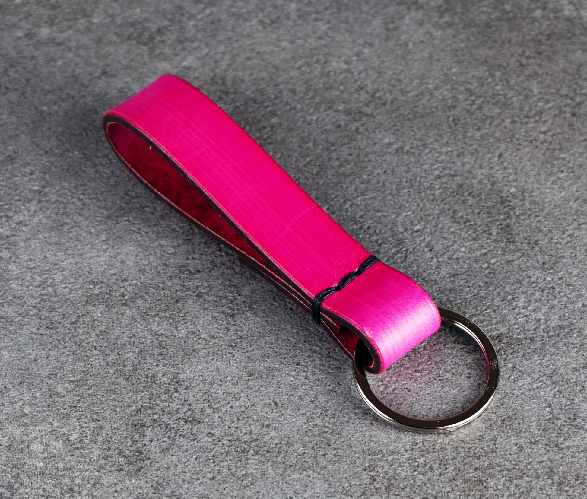 Pink leather keychain with a metal ring on a gray surface