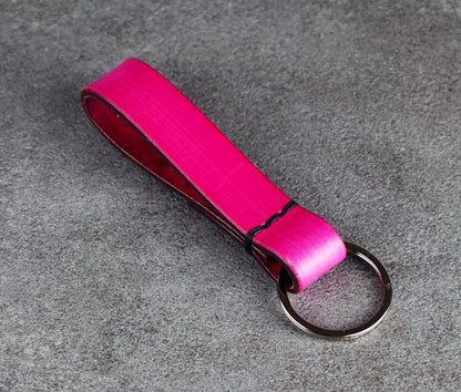 Pink leather keychain with a metal ring on a gray surface
