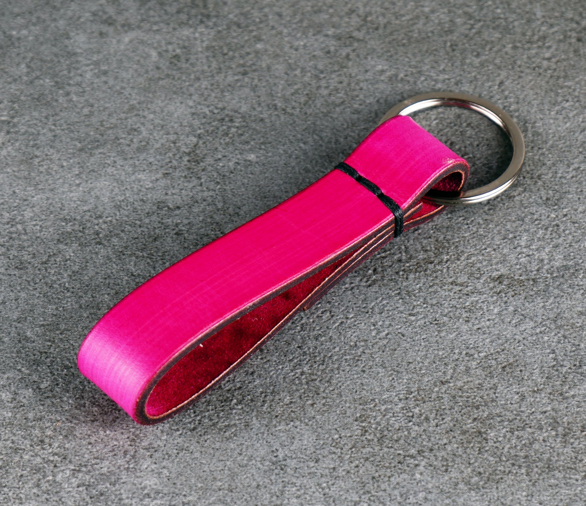 Pink leather keychain on a gray surface