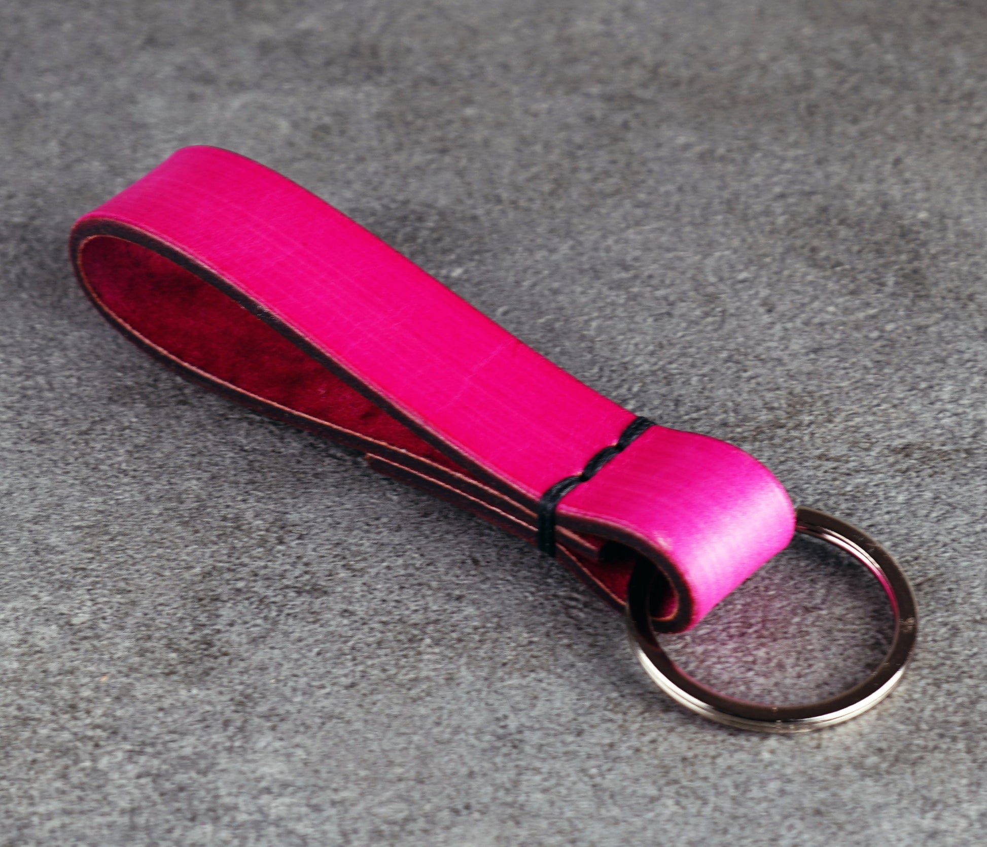 Pink leather keychain with a metal ring on a gray surface