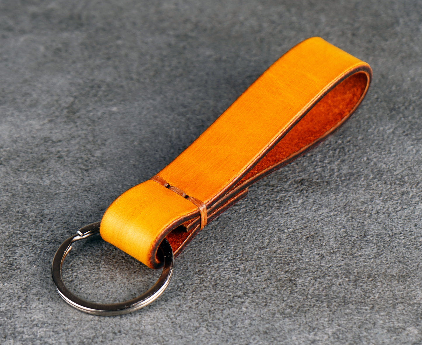 Yellow leather keychain on a gray surface