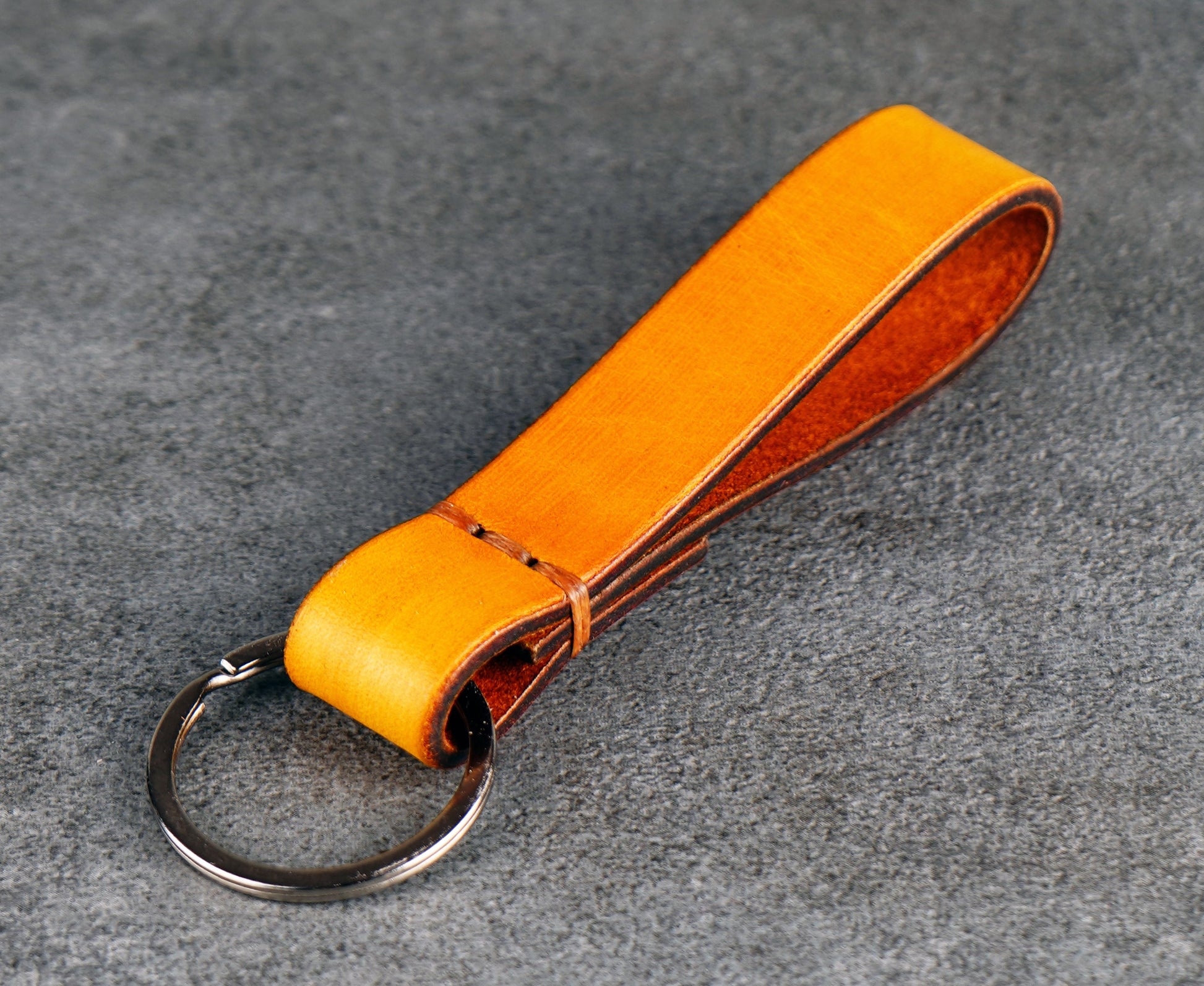 Yellow leather keychain on a gray surface