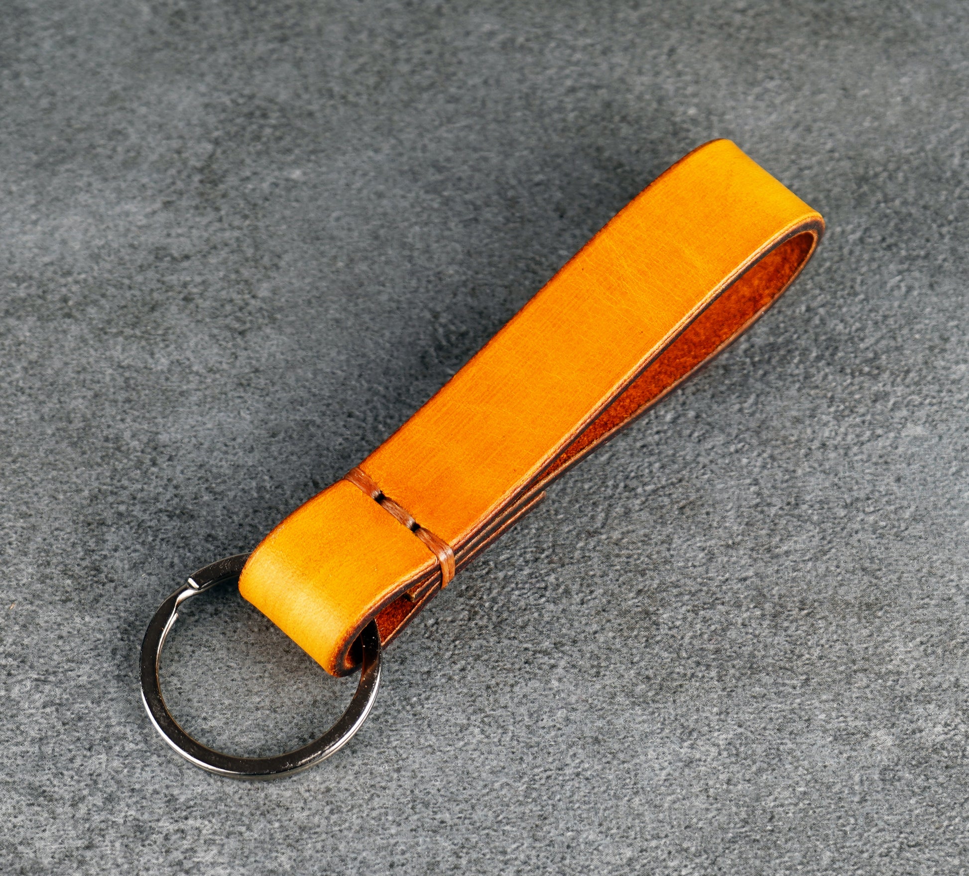 yellow leather keychain on a gray surface