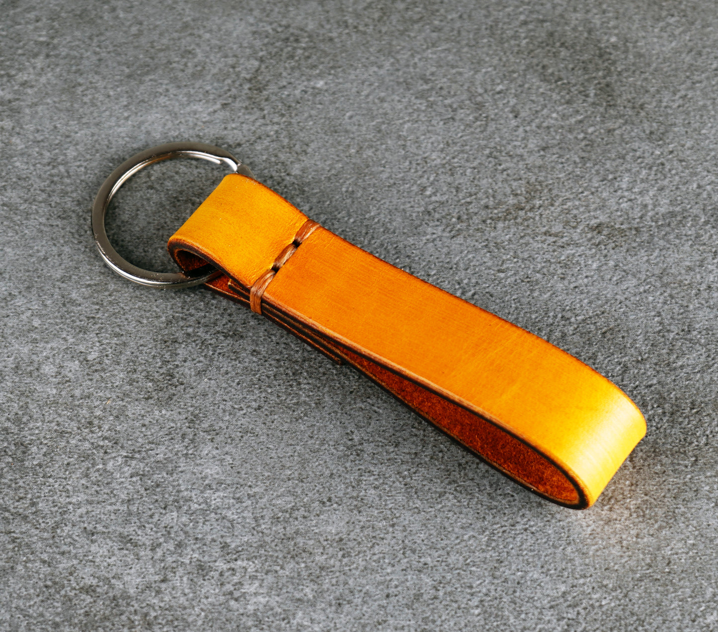 yellow leather keychain on a gray surface
