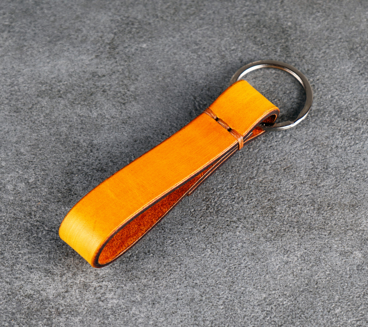 yellow leather keychain with a metal ring on a gray surface