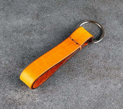 yellow leather keychain with a metal ring on a gray surface