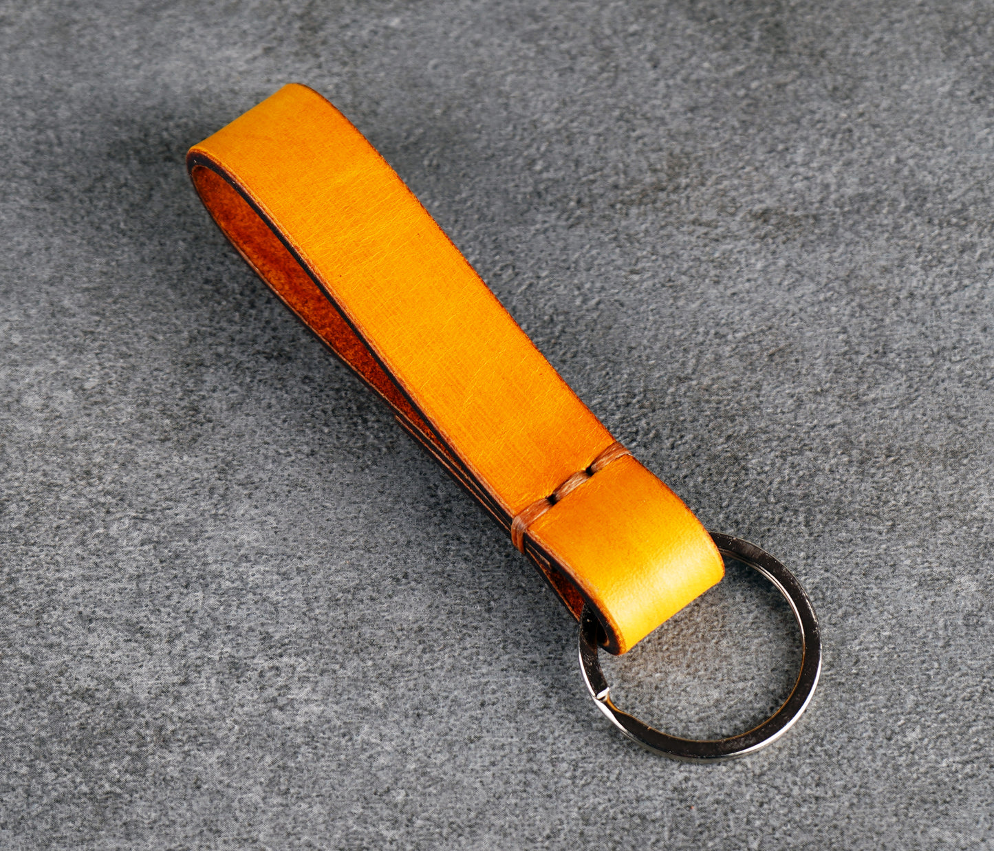 Yellow leather keychain with a metal ring on a gray surface