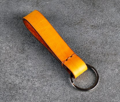 Yellow leather keychain with a metal ring on a gray surface