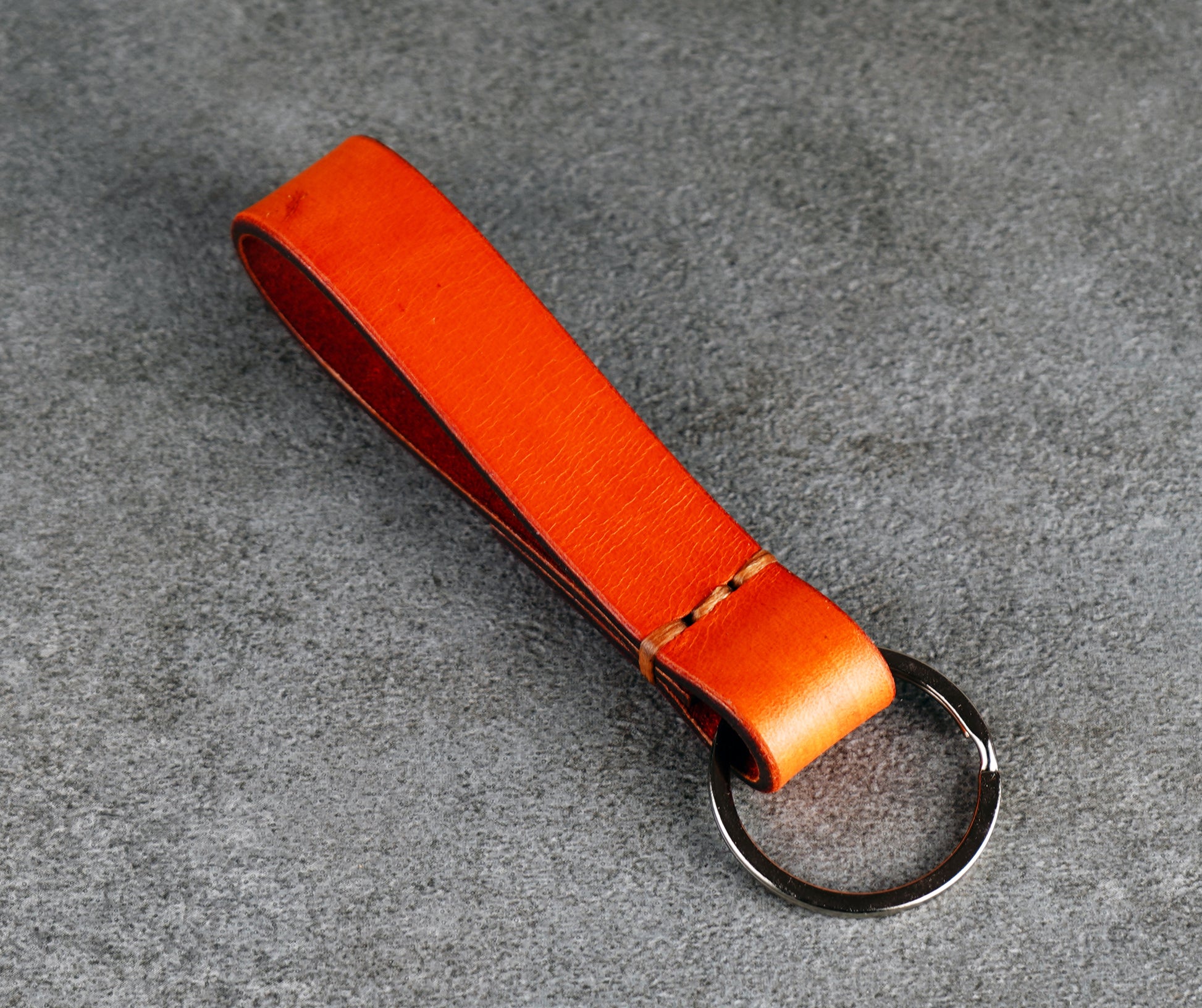 Orange leather keychain on a gray surface