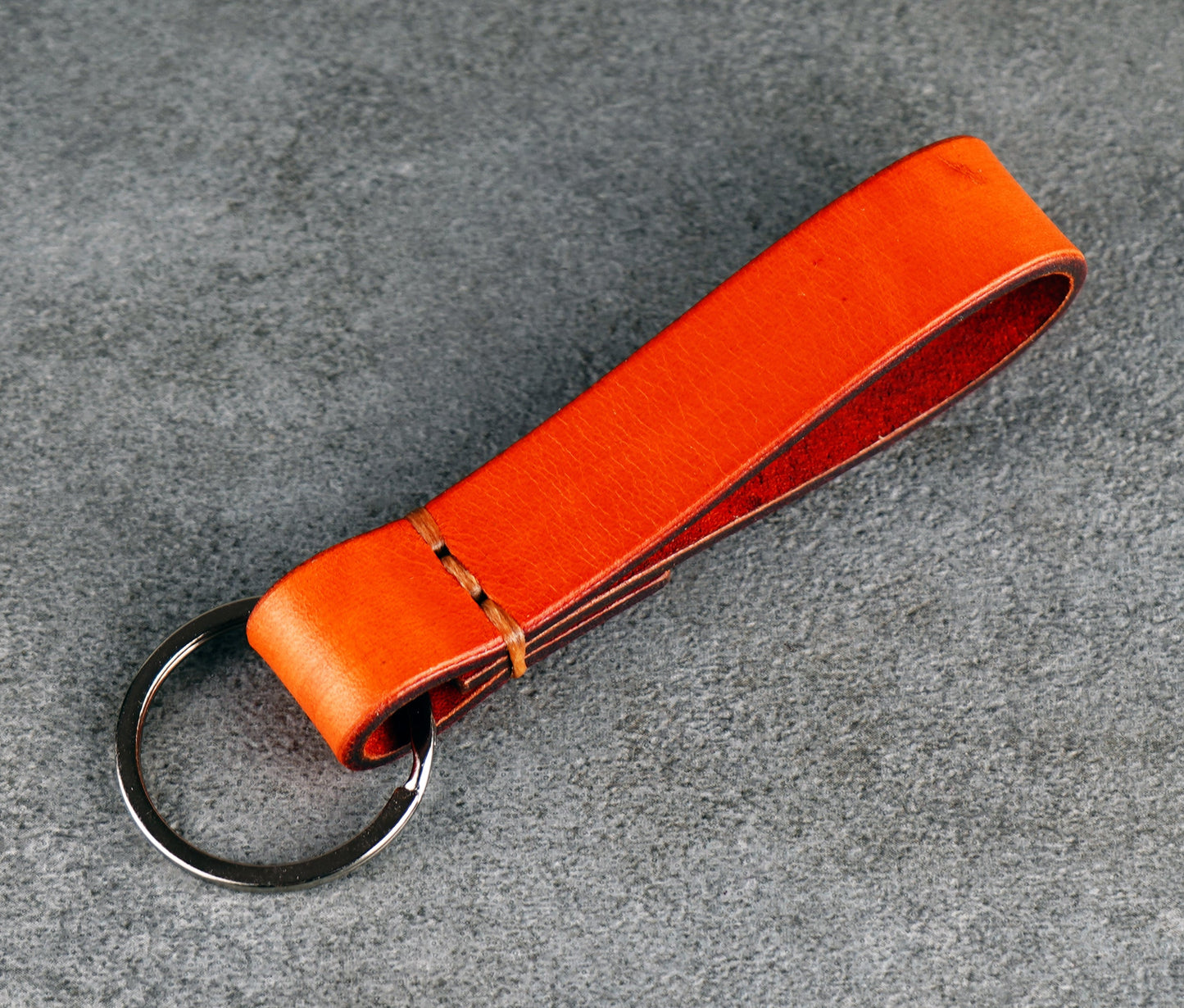 Orange leather keychain on a gray textured background