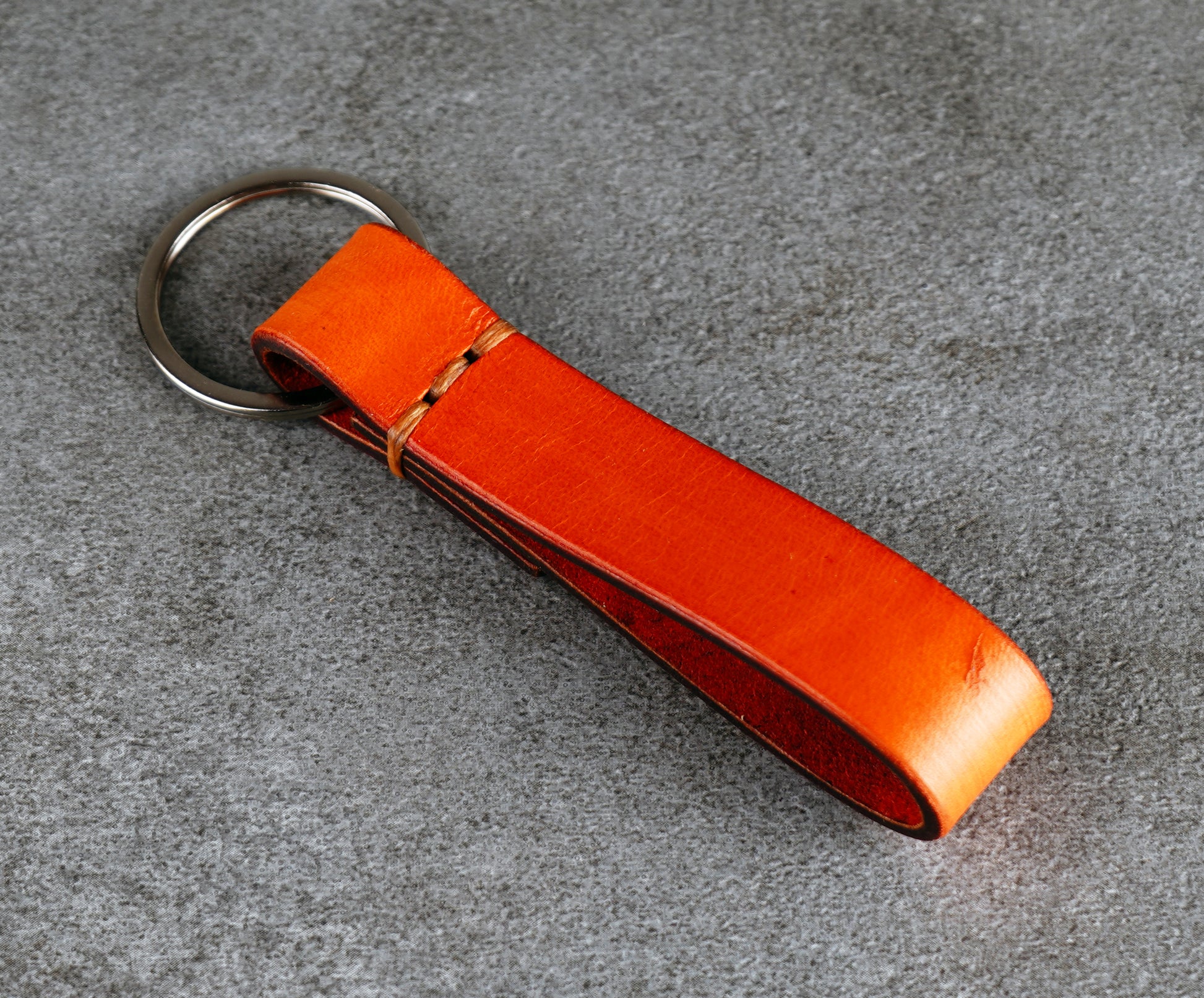 Orange leather keychain on a gray surface