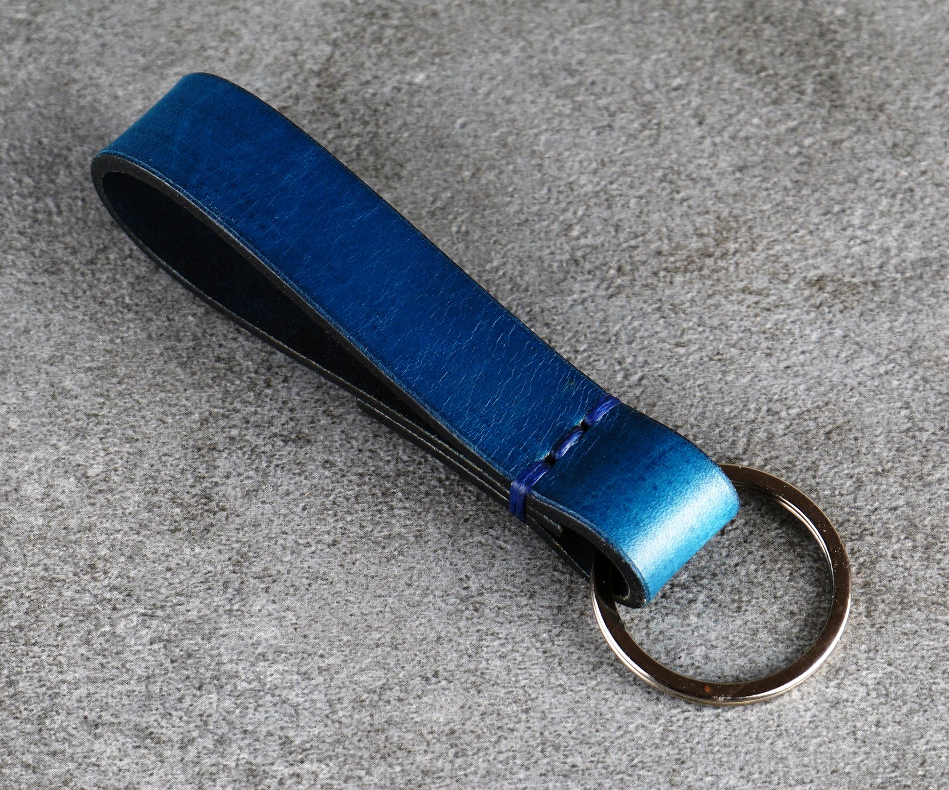 Blue leather key fob on a gray surface