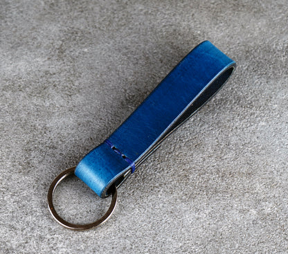 Blue leather keychain on a gray concrete surface