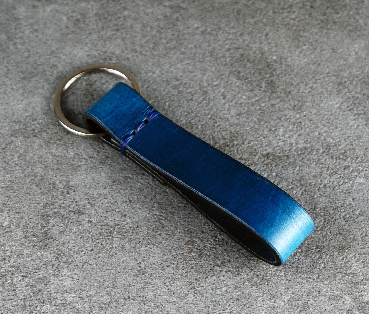 Blue leather key fob on a gray surface