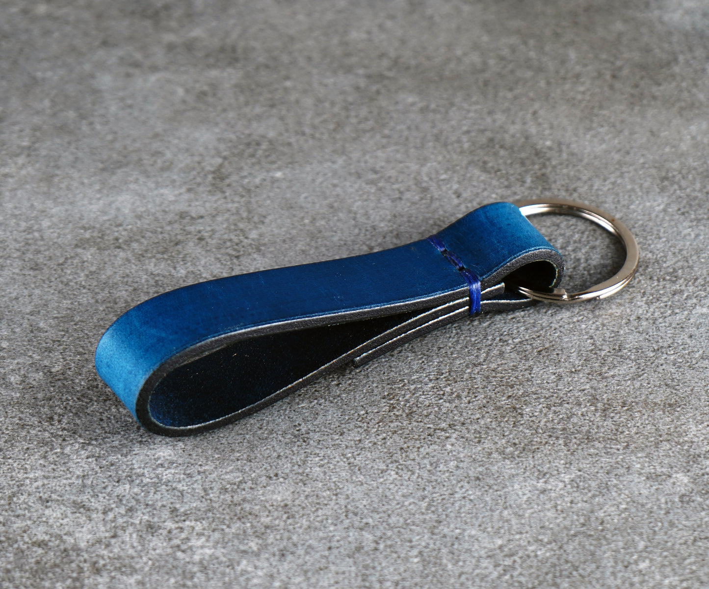 Blue leather keychain on a gray surface
