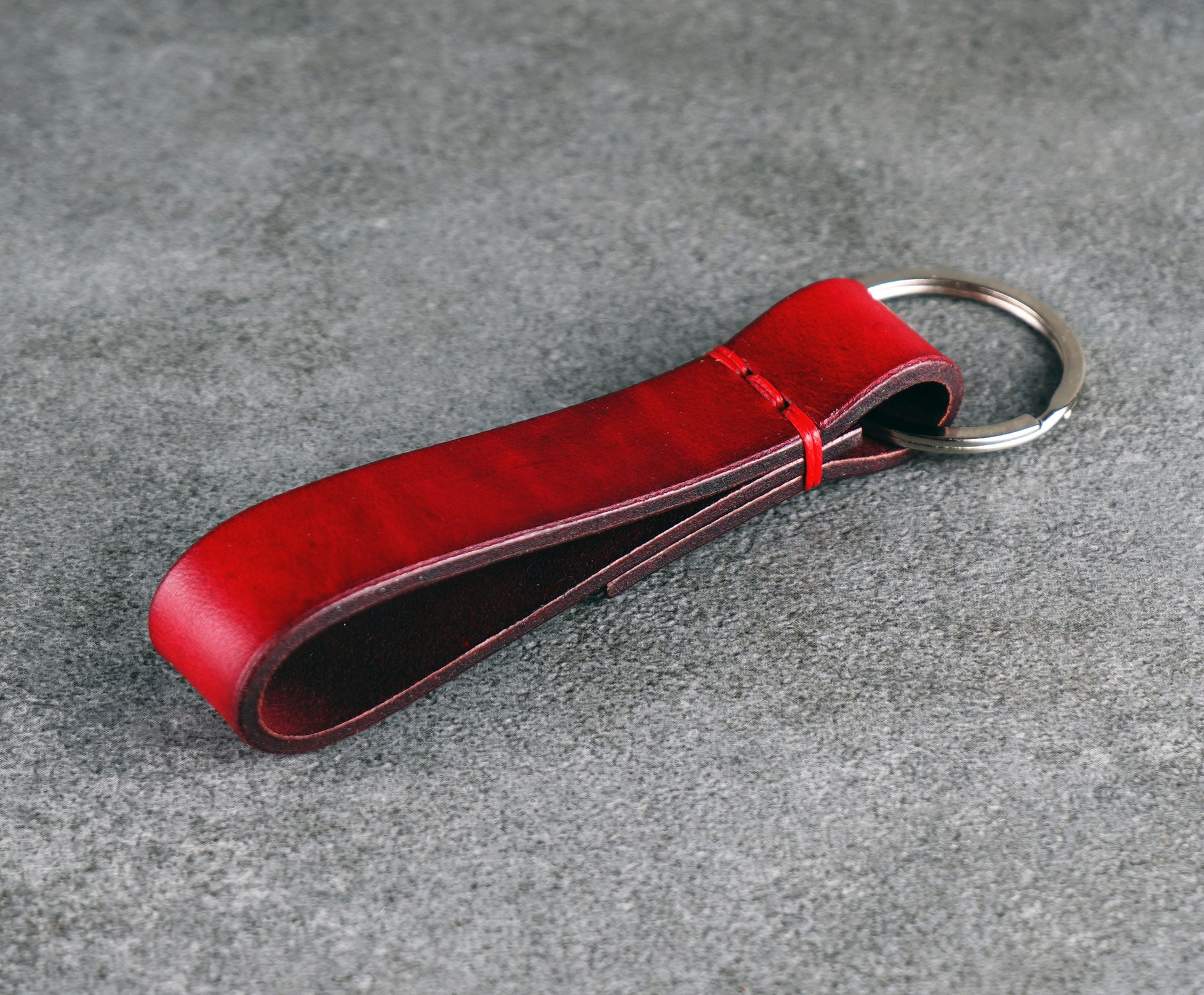 Red leather keychain on a gray surface