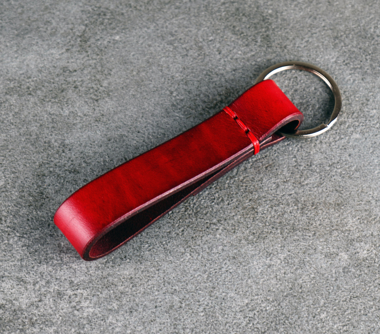 Red leather keychain on a gray surface