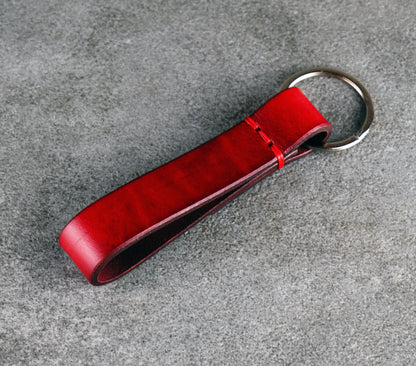 Red leather keychain on a gray surface