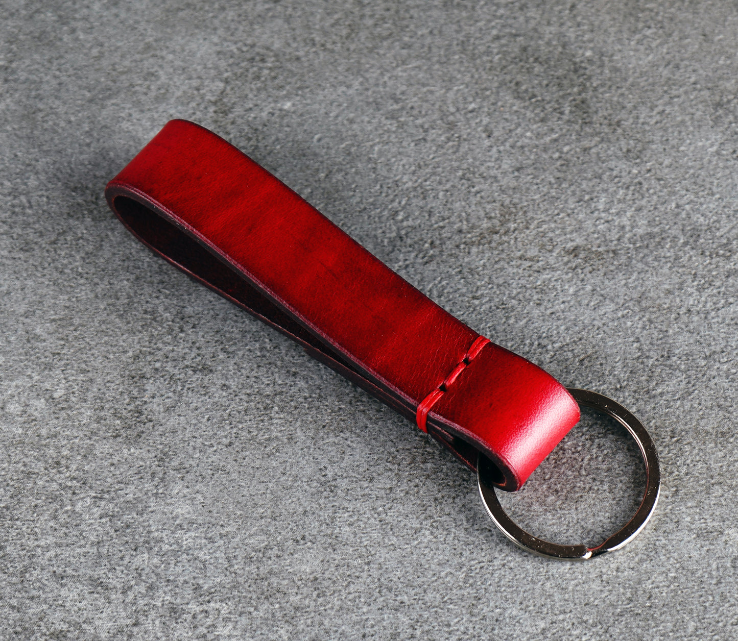 Red leather keychain on a gray surface