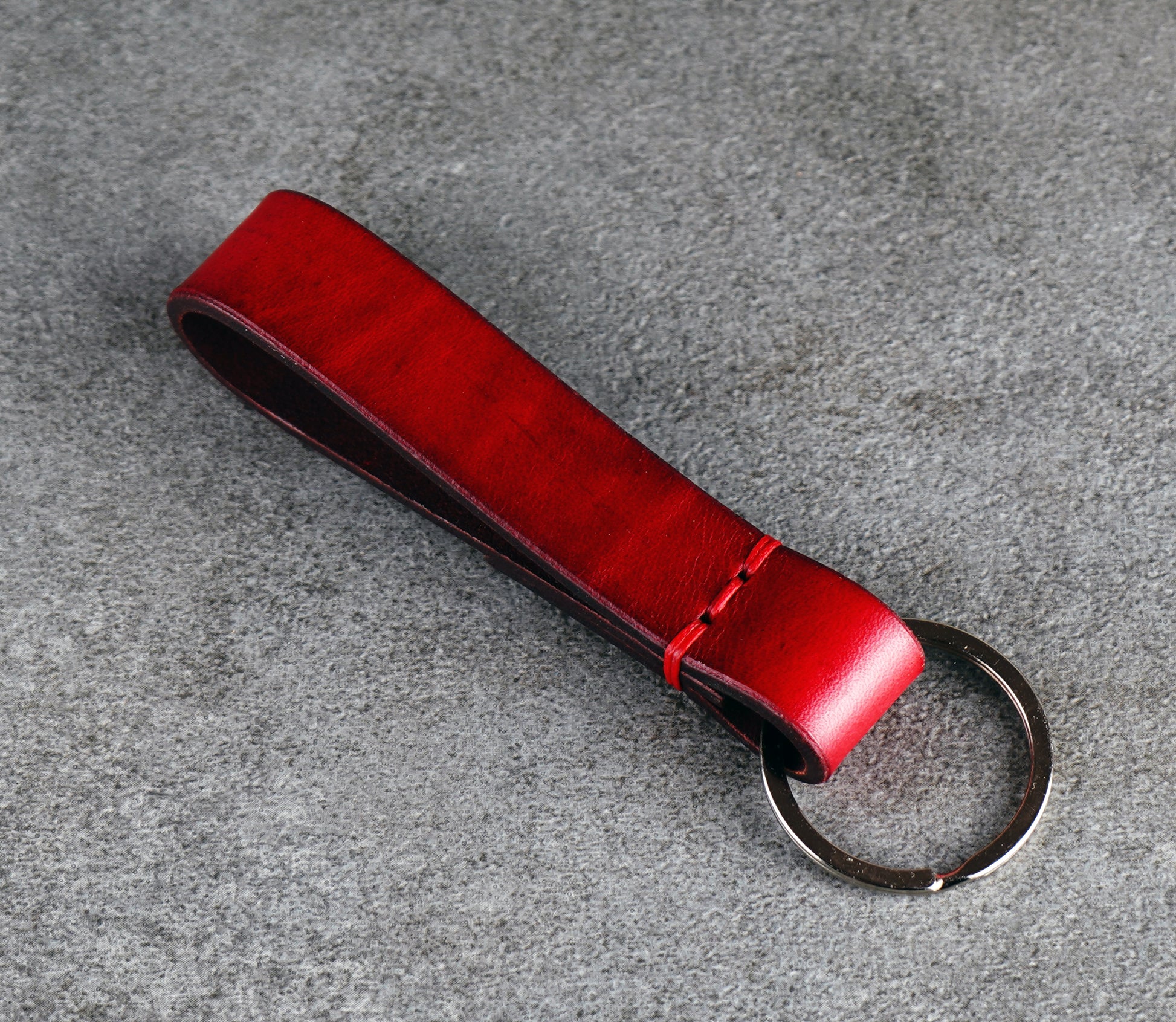 Red leather keychain on a gray surface