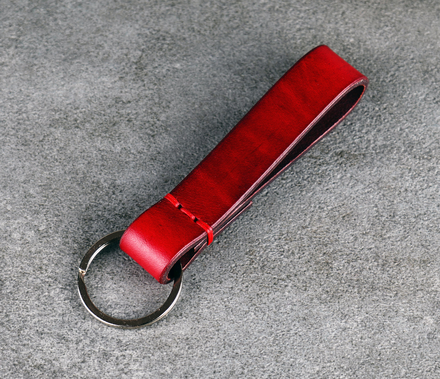 Red leather keychain on a gray concrete surface
