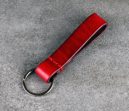 Red leather keychain on a gray concrete surface