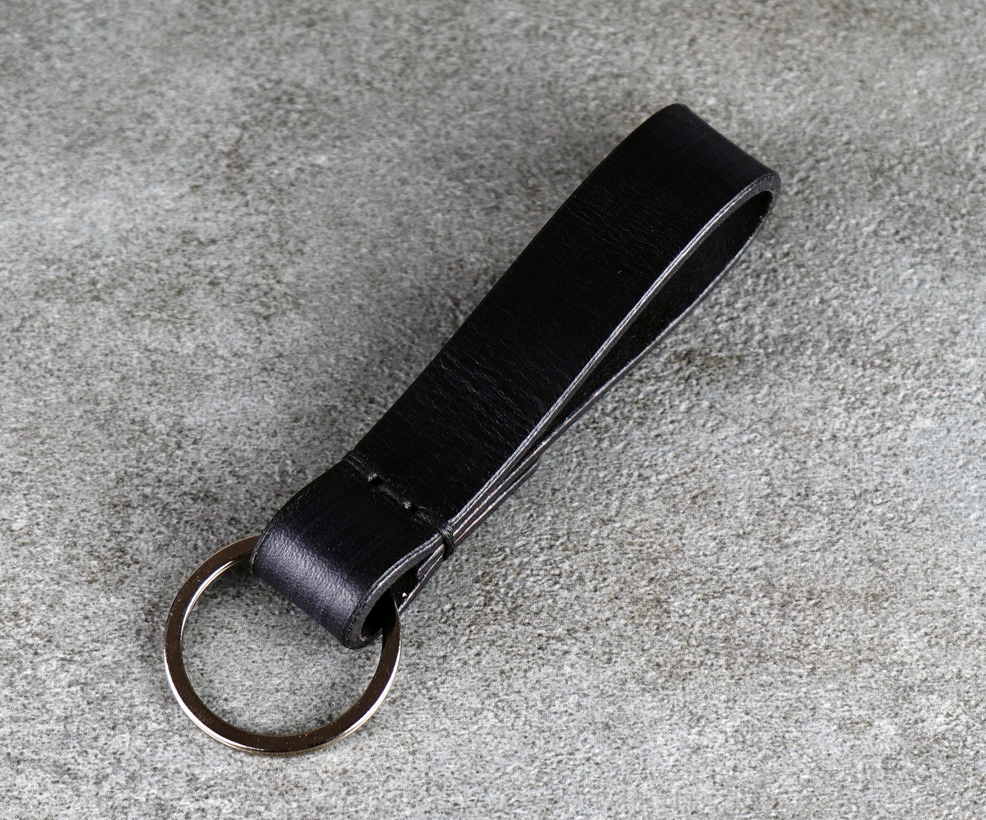 Black leather keychain on a gray concrete surface