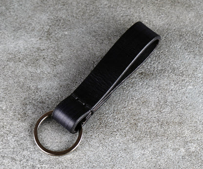 Black leather keychain on a gray concrete surface
