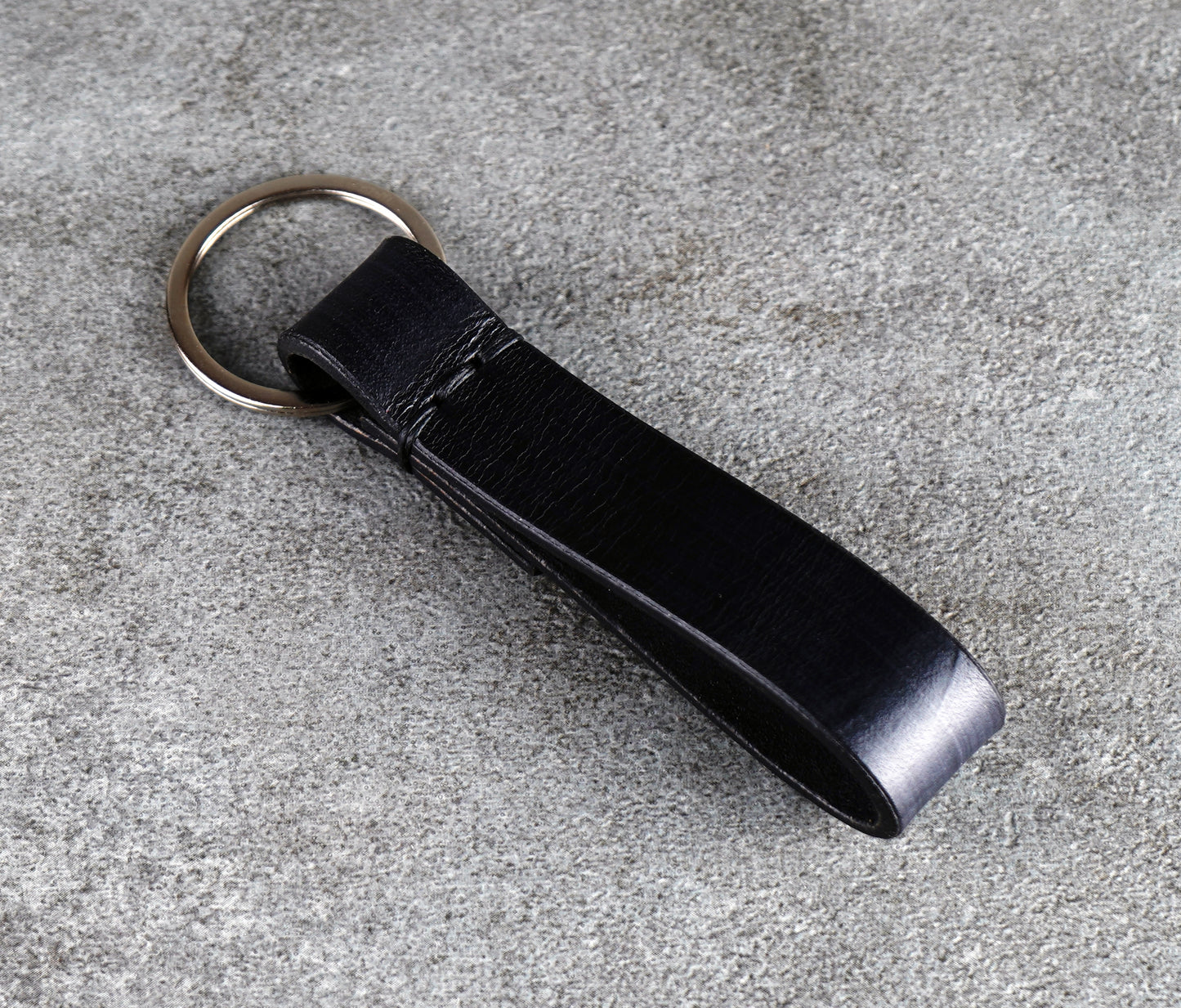 Black leather keychain on a gray concrete surface