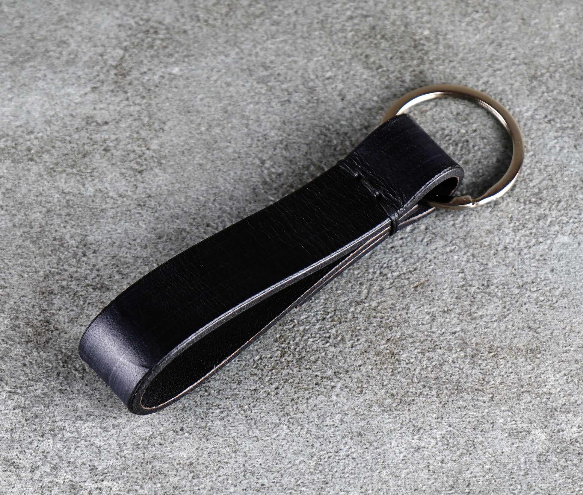 Black leather key fob on a gray concrete surface