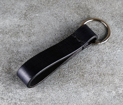 Black leather key fob on a gray concrete surface