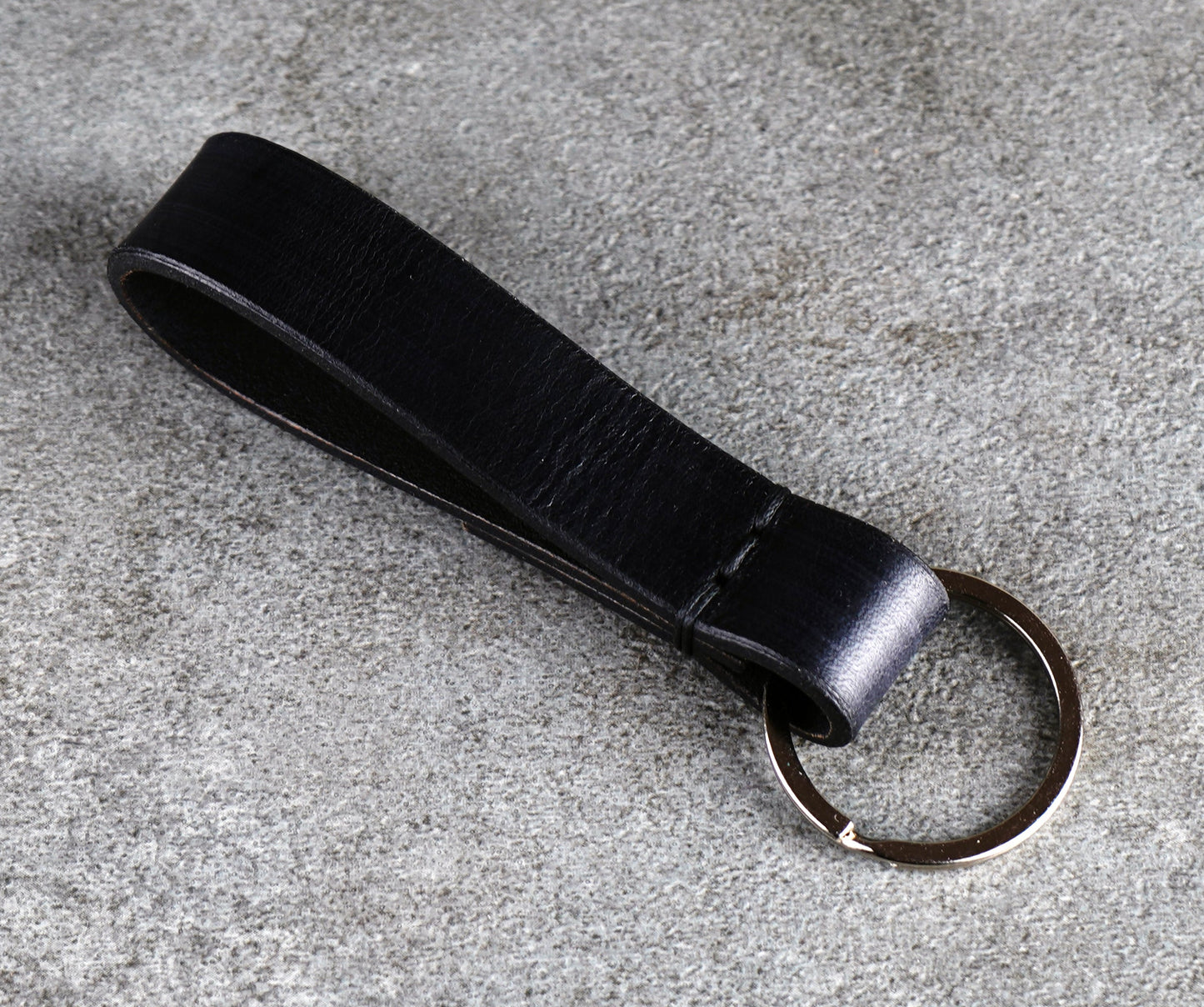 Black leather keychain on a gray surface