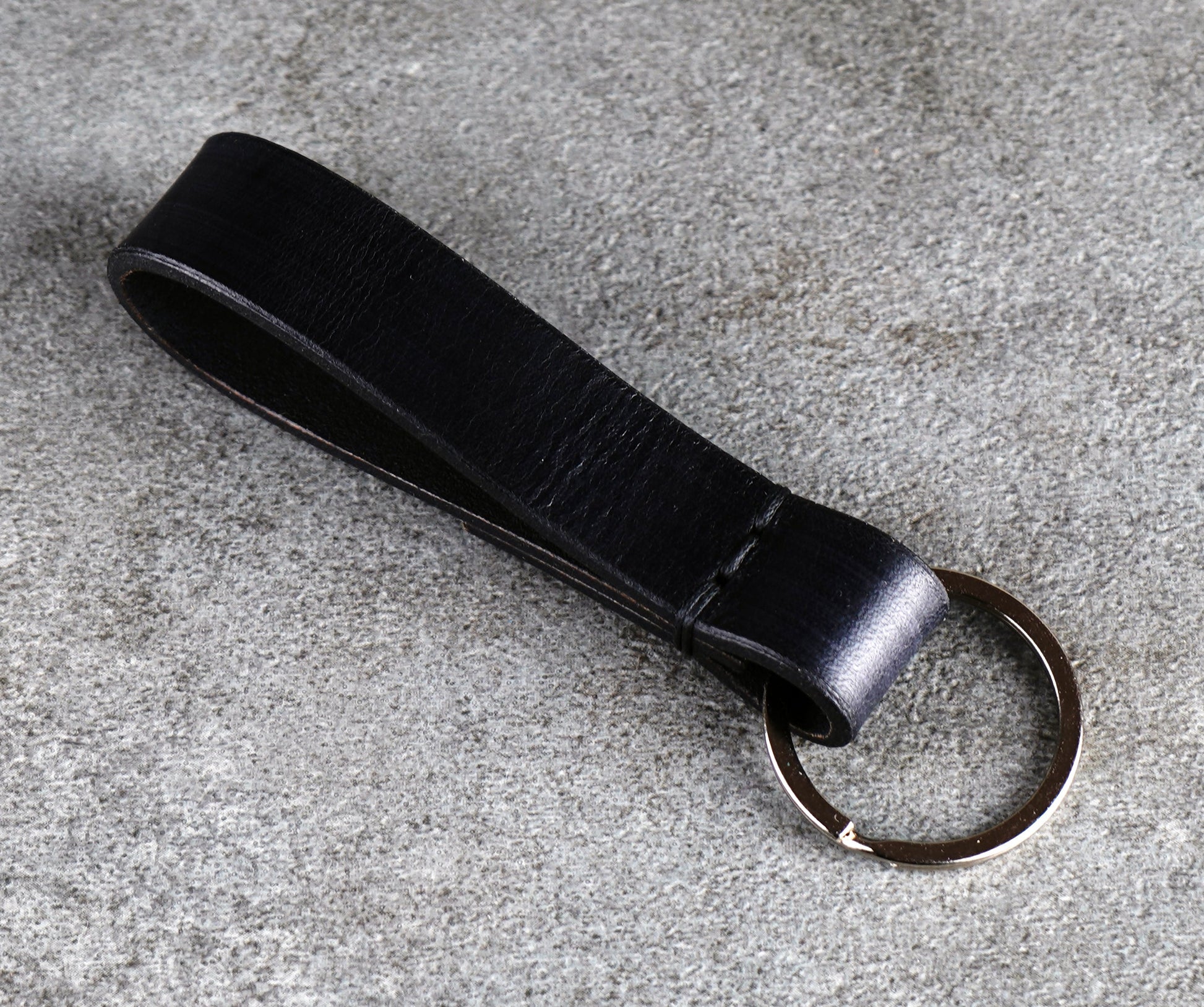 Black leather keychain on a gray surface