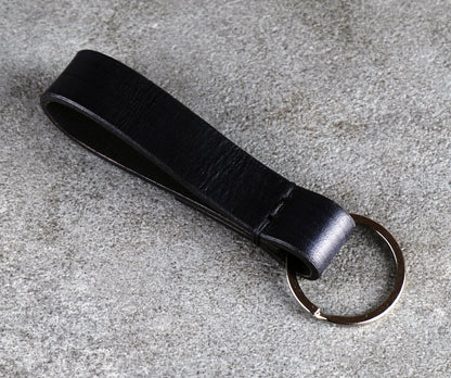 Black leather keychain on a gray surface