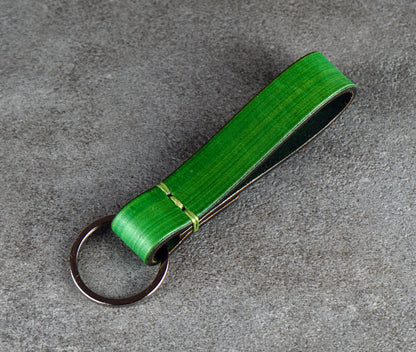 Green leather keychain on a gray surface