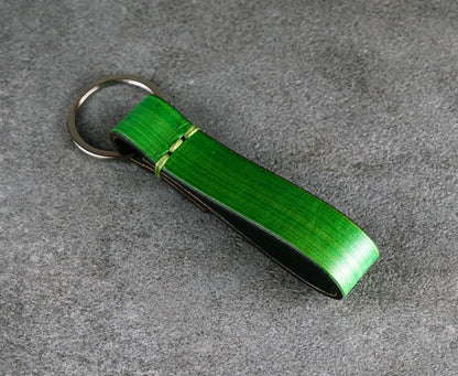 Green leather keychain on a gray surface
