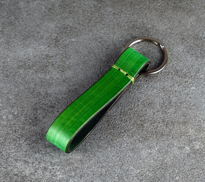 Green leather keychain with a metal clip on a gray surface