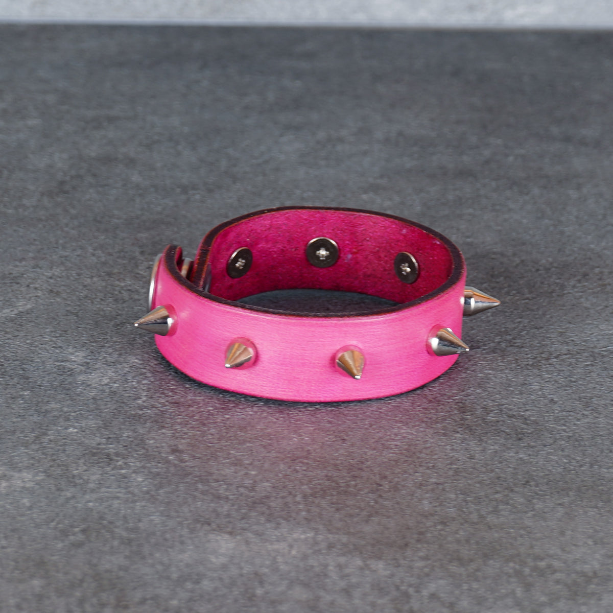 Spiked pink leather bracelet shown from a front-facing studio view