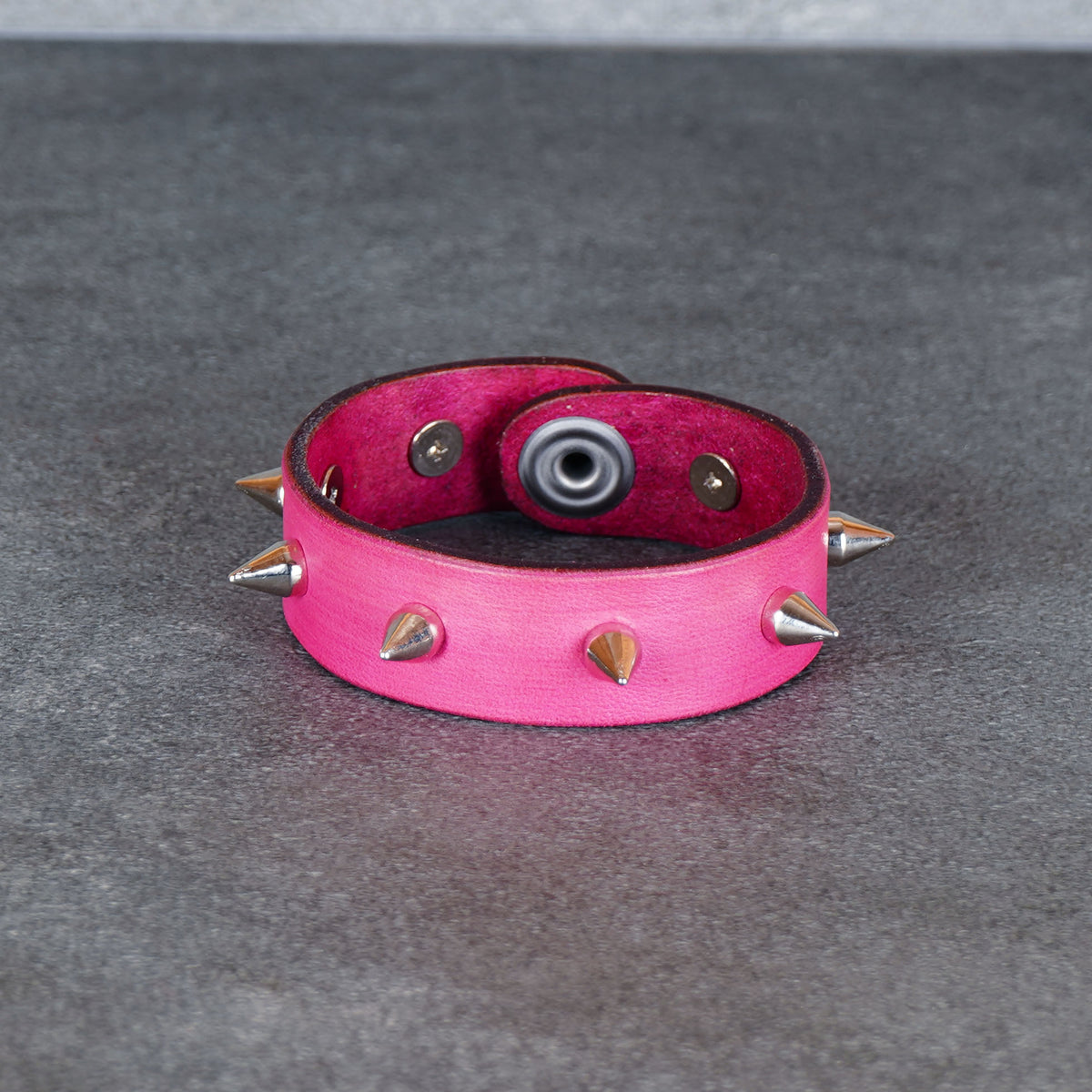 Pink spiked leather bracelet shown open with the snap fastener visible