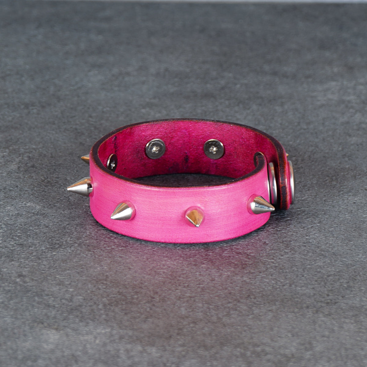 Pink cuff bracelet displayed from the back with spike details along the edge