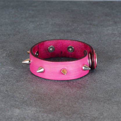 Pink cuff bracelet displayed from the back with spike details along the edge