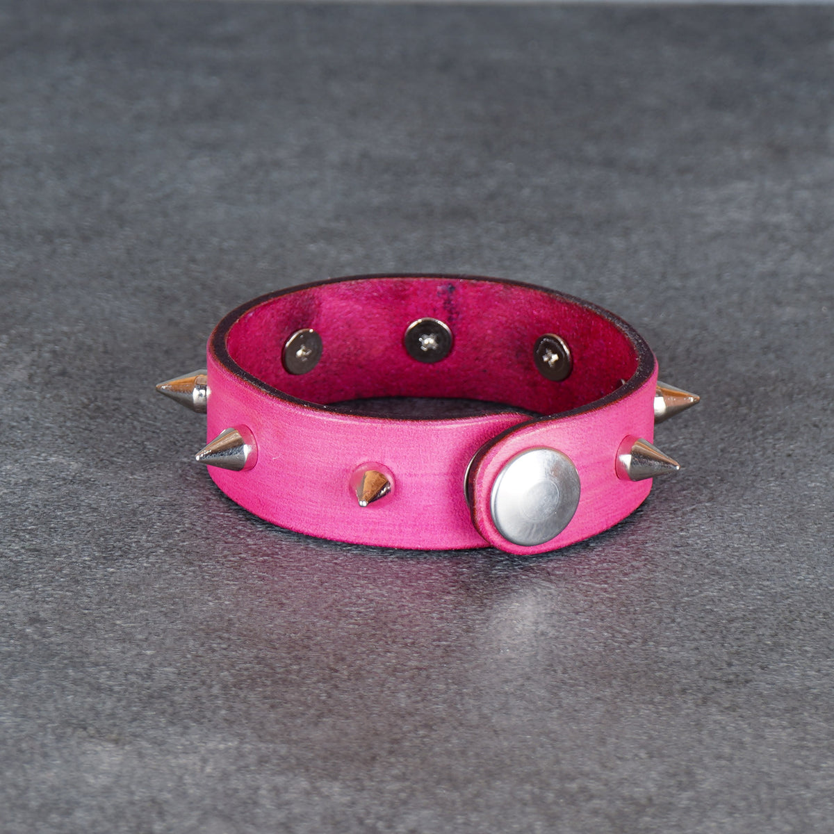 Pink spiked bracelet with a visible snap stud on the side