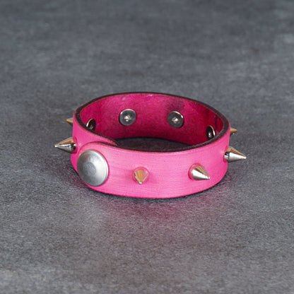 Pink spiked leather bracelet from a low front angle with the snap stud visible