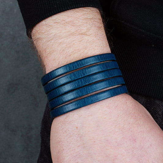 Blue leather wrap bracelet on gray background, handmade genuine leather cuff bracelet with layered strap design, minimalist blue wristband accessory for men and women
