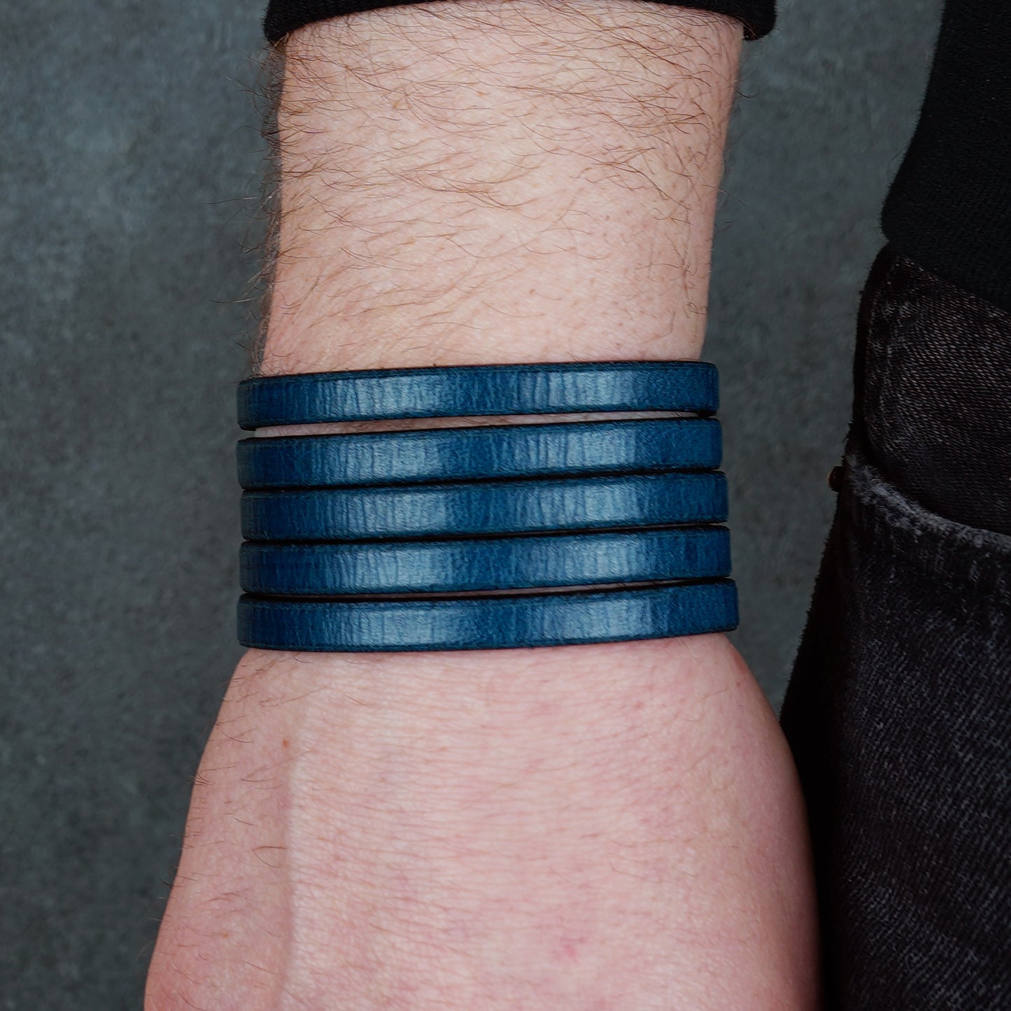Blue leather wrap bracelet on gray background, handmade genuine leather cuff bracelet with layered strap design, minimalist blue wristband accessory for men and women
