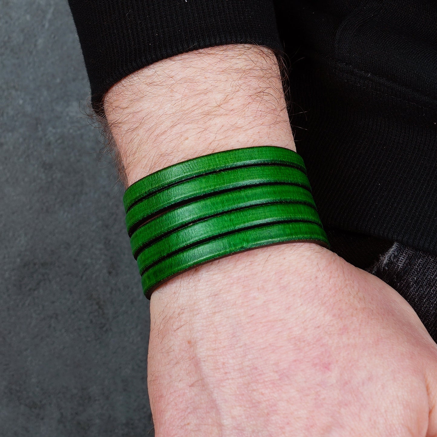 Green leather wrap bracelet on gray background, handmade genuine leather cuff bracelet with layered design, minimalist green wristband accessory for men and women
