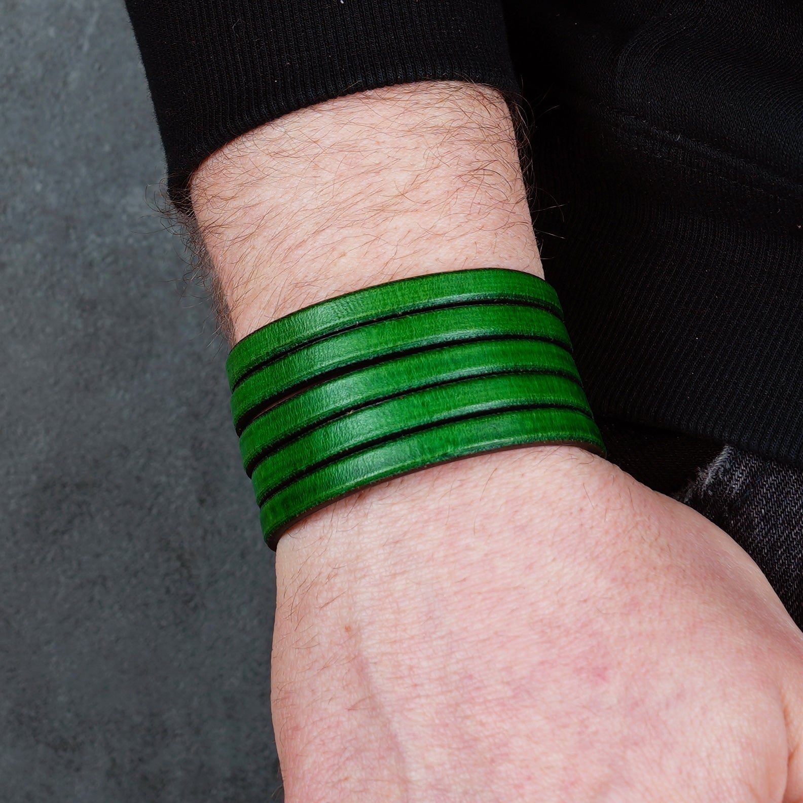 Green leather wrap bracelet on gray background, handmade genuine leather cuff bracelet with layered design, minimalist green wristband accessory for men and women
