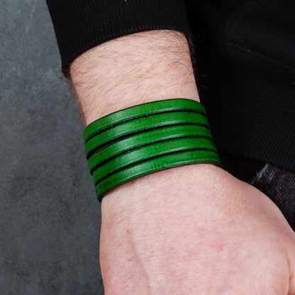 Green leather wrap bracelet on gray background, handmade genuine leather cuff bracelet with layered design, minimalist green wristband accessory for men and women
