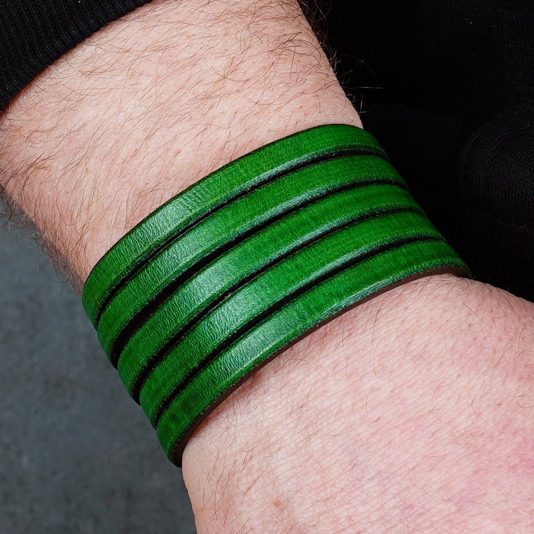 Green leather wrap bracelet on gray background, handmade genuine leather cuff bracelet with layered design, minimalist green wristband accessory for men and women
