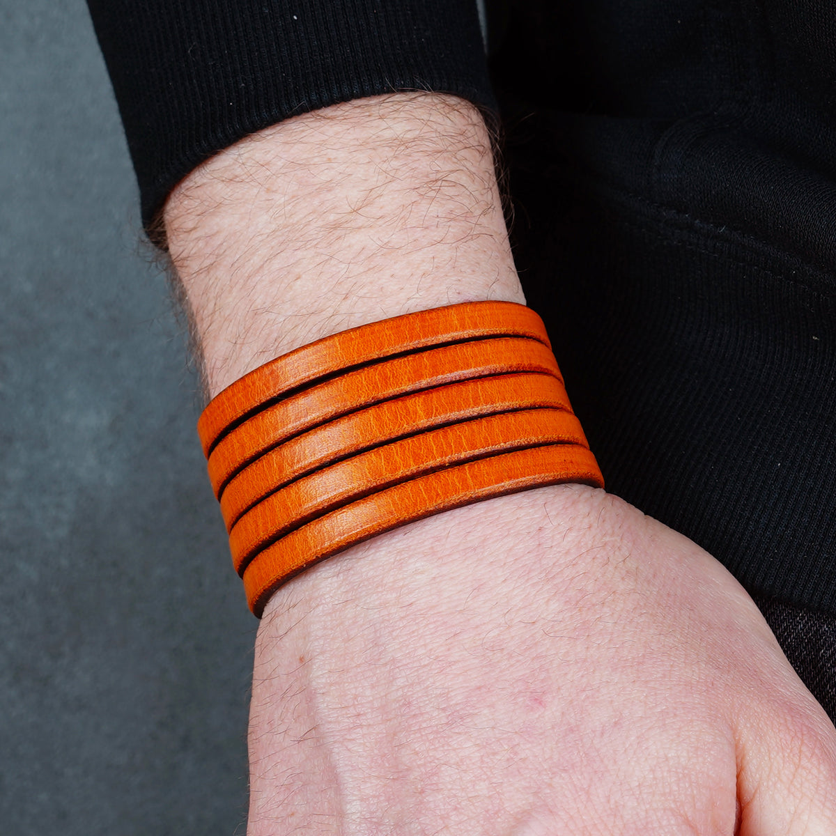 Orange leather cuff bracelet worn from above on a wrist